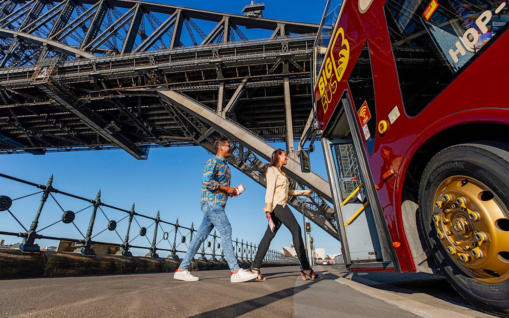 Visitors boarding Big Bus Sydney at Dawes Point with Sydney Harbour Bridge in the background.