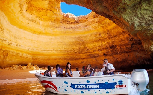 Boat tour inside Benagil Cave, Algarve, with tourists exploring rock formations.