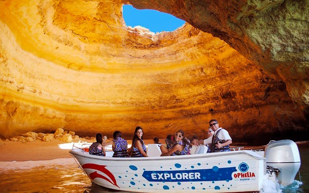 Boat tour inside Benagil Cave, Algarve, with tourists exploring rock formations.