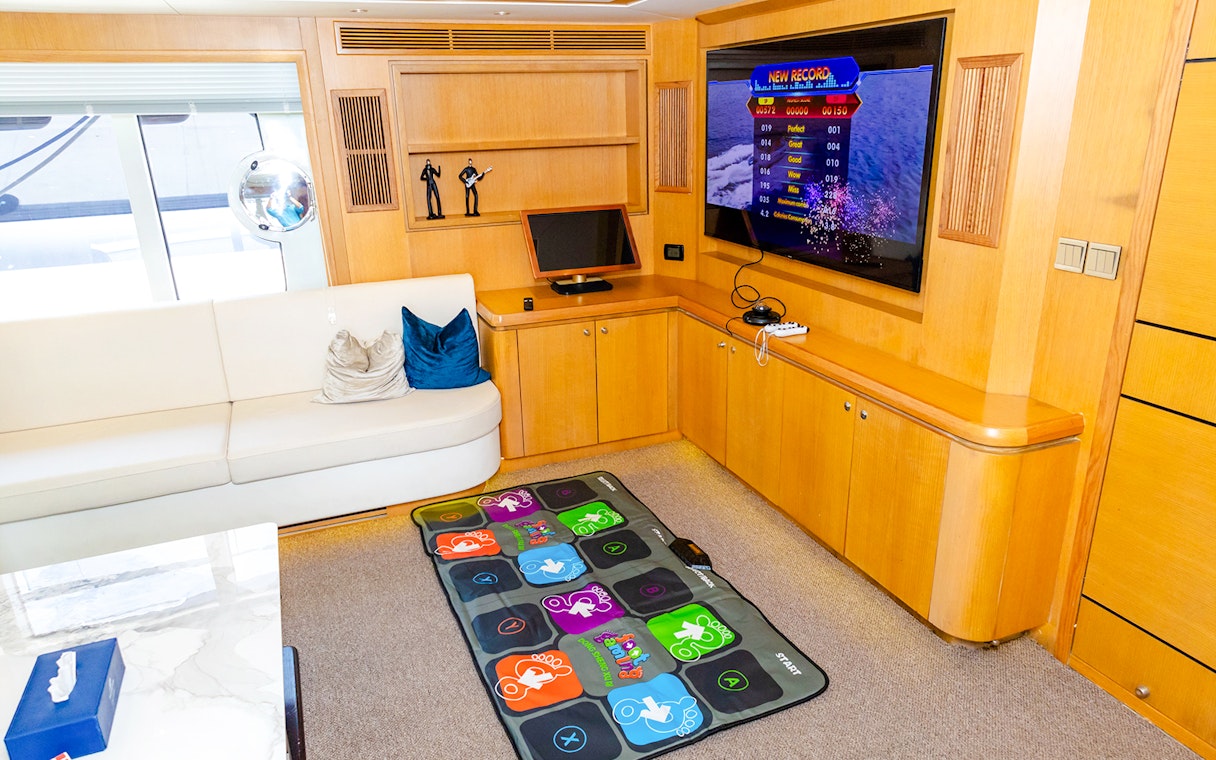 Yacht interior with entertainment area, TV, gaming mat, and seating.