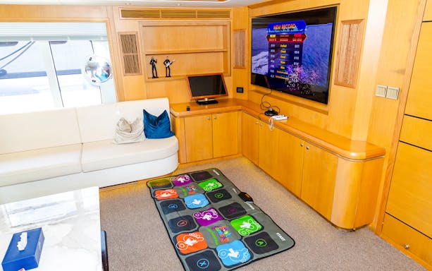 Yacht interior with entertainment area, TV, gaming mat, and seating.