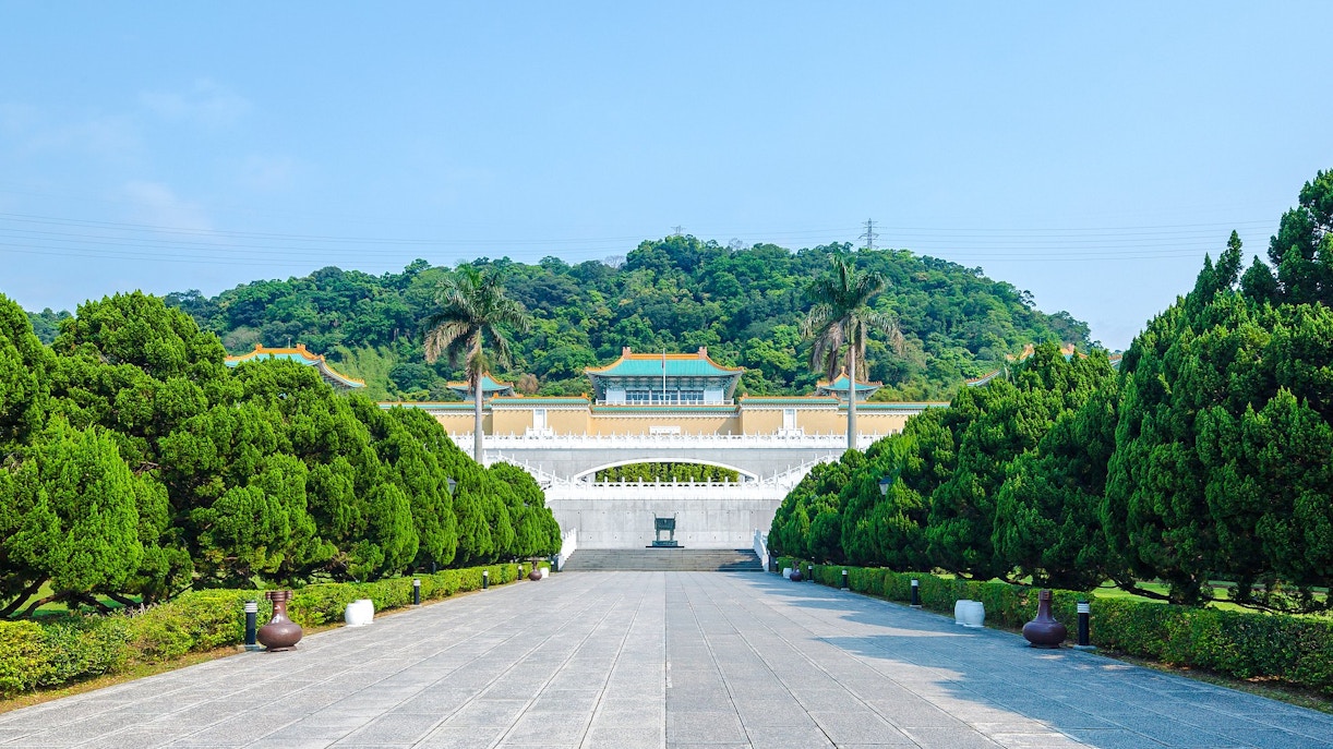 Taiwan Palace Museum entrance with lush greenery and distant hills.