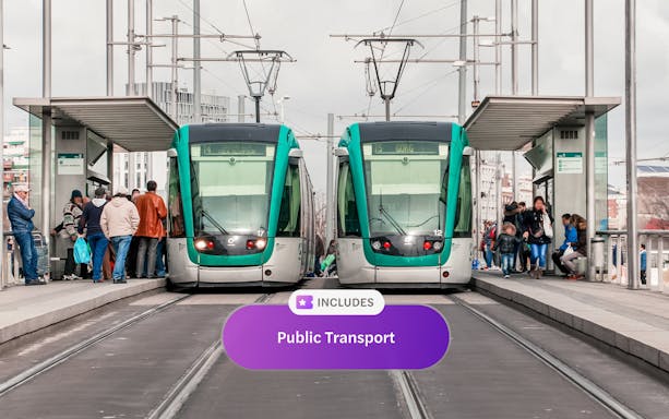 Tourists boarding trams at a Barcelona station with cityscape views.