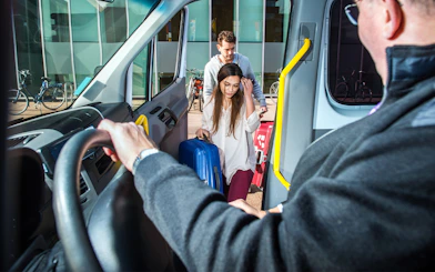 Passengers boarding a shuttle with luggage for Katowice Airport to Krakow transfer.