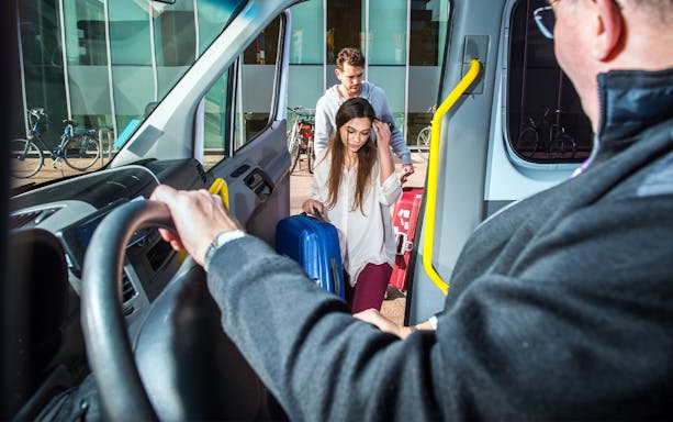 Passengers boarding a shuttle with luggage for Katowice Airport to Krakow transfer.