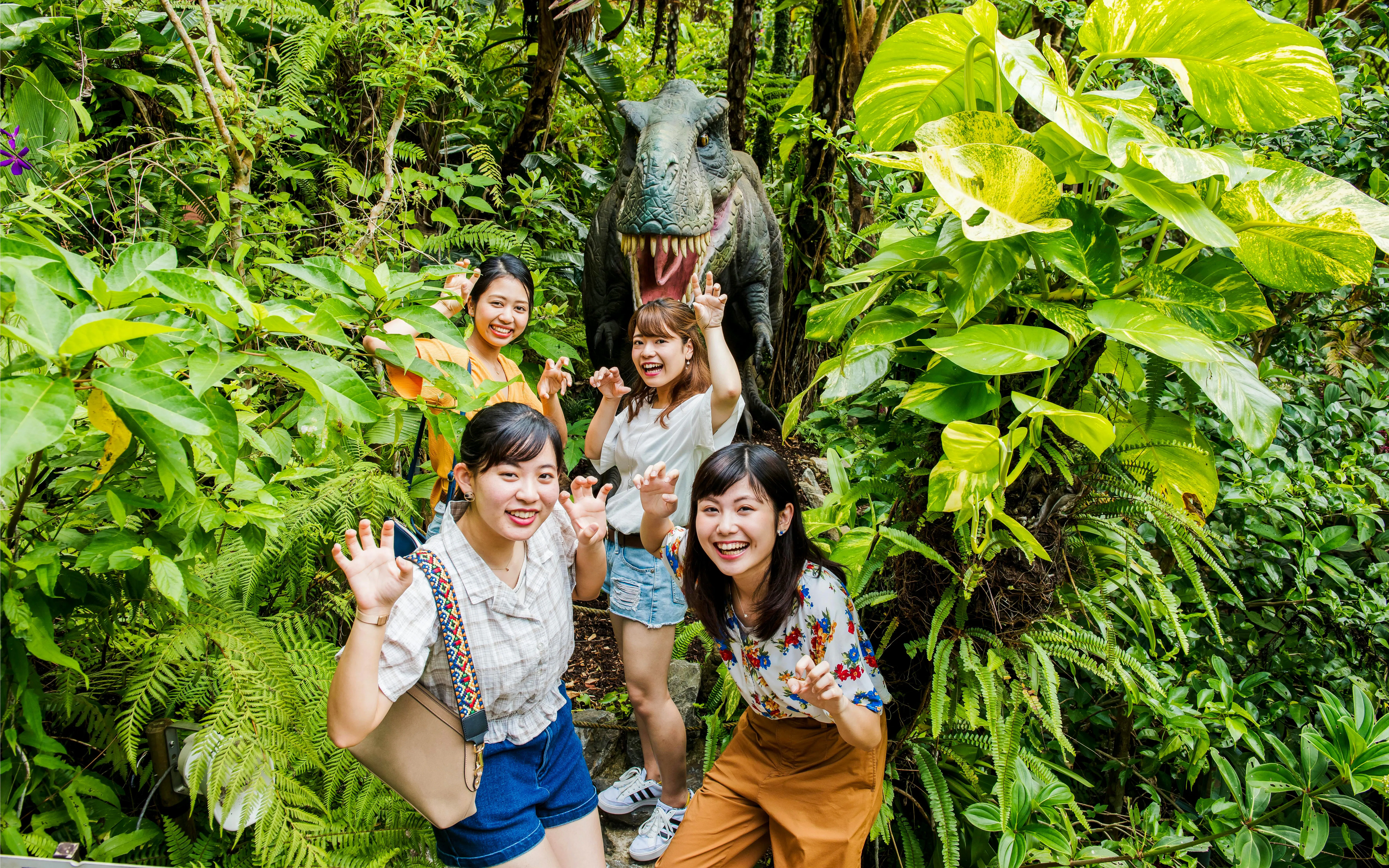Visitors posing with dinosaur statue in Okashigoten Nago Dino Park, Yanbaru Subtropical Forest.