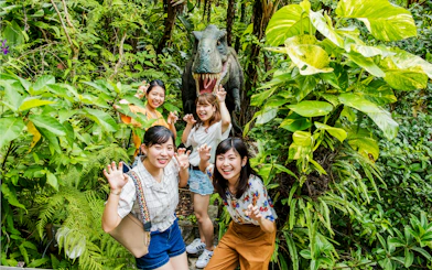 Visitors posing with dinosaur statue in Okashigoten Nago Dino Park, Yanbaru Subtropical Forest.