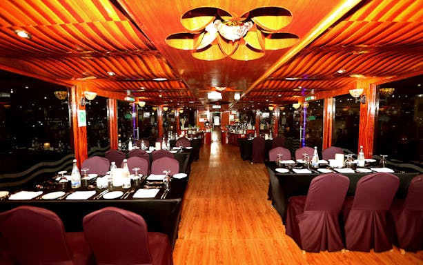 Elegant dining setup on Abu Dhabi Dhow Dinner Cruise with wooden interiors.