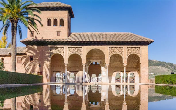 Alcazaba arches reflected in Alhambra garden pool, Granada, Spain.