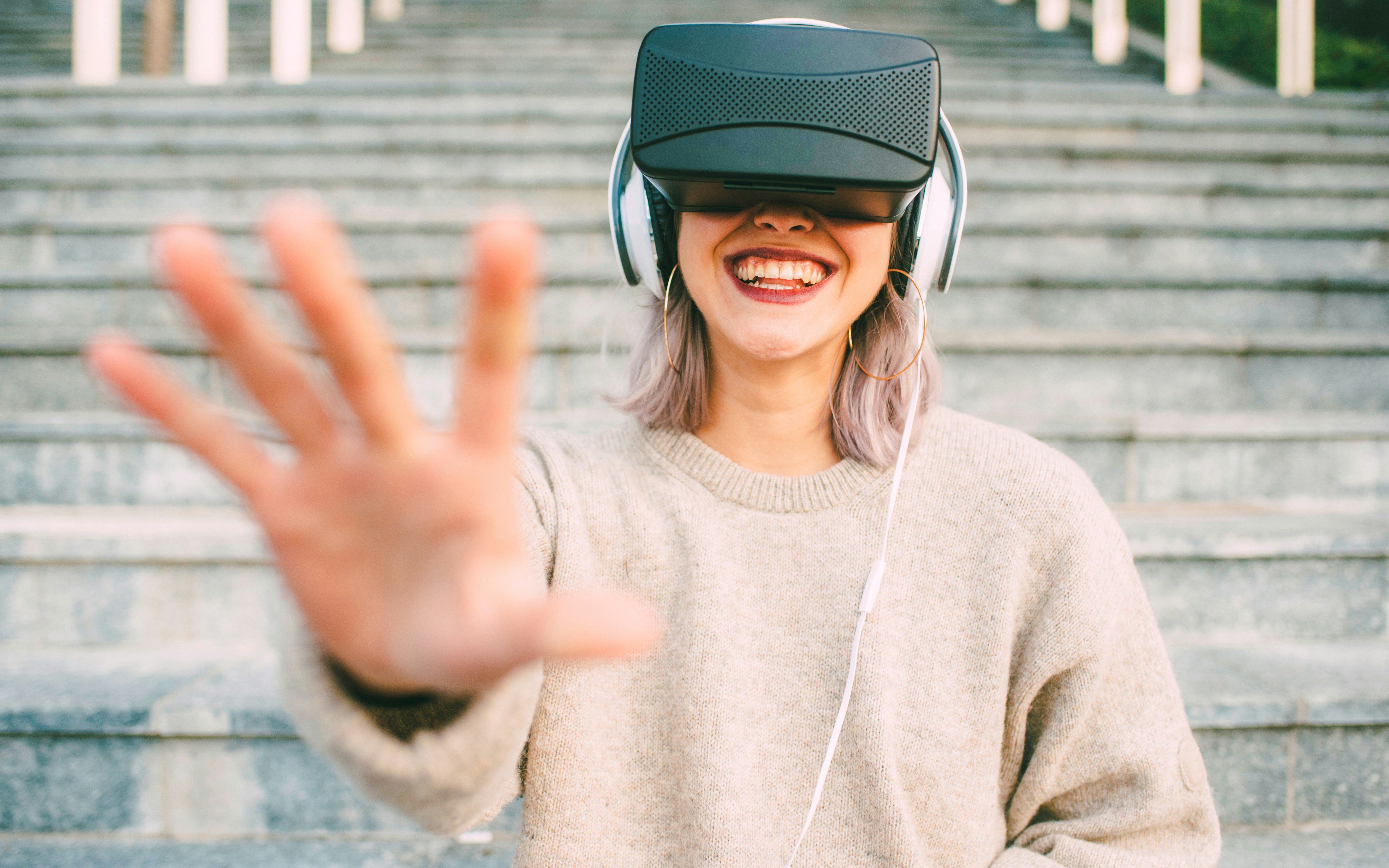 Young woman enjoying VR experience outdoors on steps.