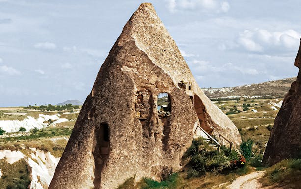 Ancient rock formation in Cappadocia with carved windows, part of guided day tour.