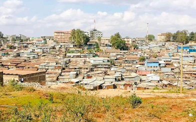 Kibera slum landscape in Nairobi, showcasing densely packed rooftops and surrounding greenery.