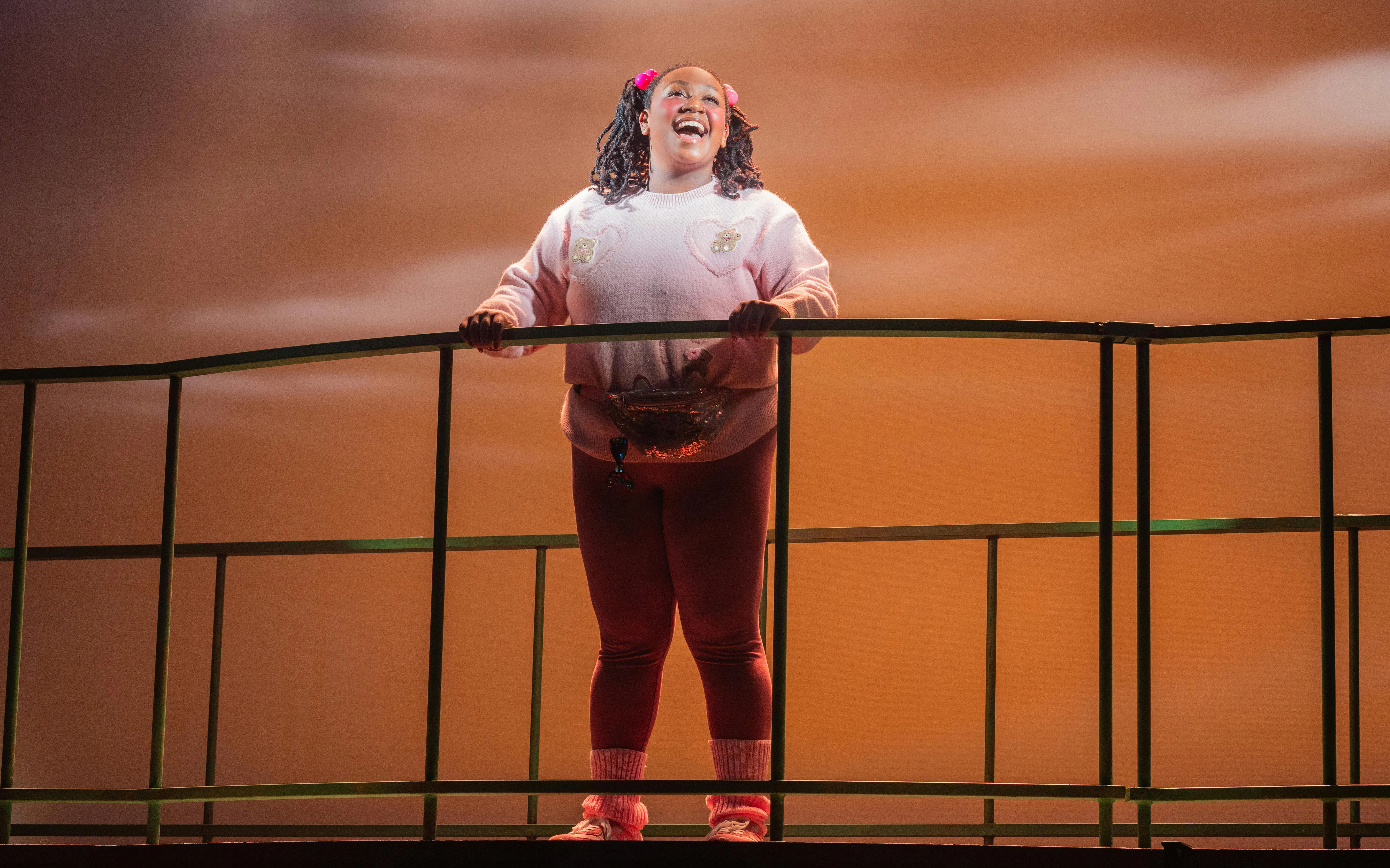 Performer on stage during Heathers The Musical, standing on a balcony set.
