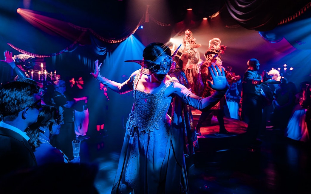 Masquerade ball scene from Broadway performance with masked dancers on stage.