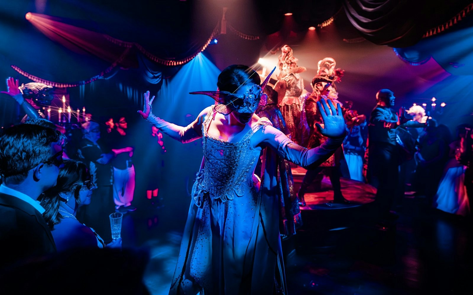 Masquerade ball scene from Broadway performance with masked dancers on stage.