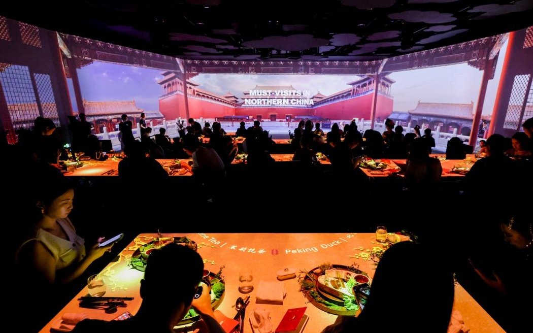 People dining at "Taste of China" immersive restaurant, Shanghai, with Northern China visuals.