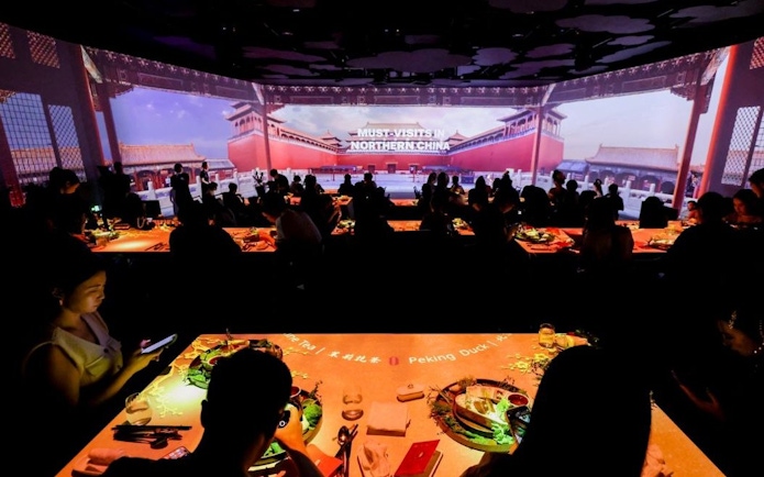 People dining at "Taste of China" immersive restaurant, Shanghai, with Northern China visuals.