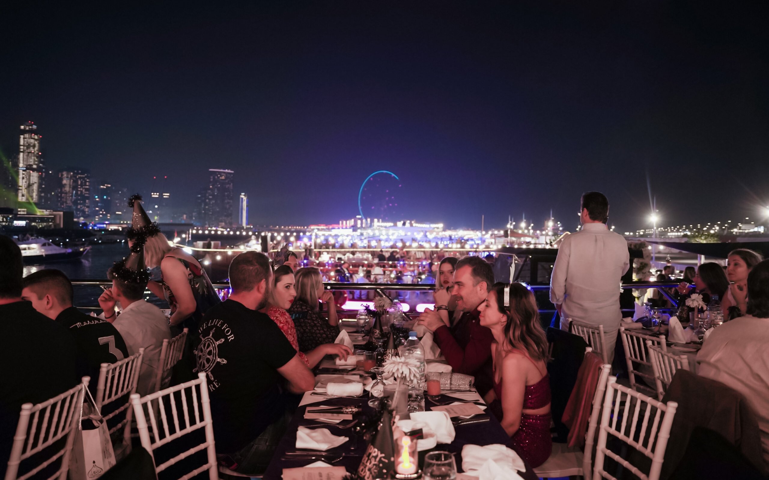 Guests dining on a New Year's Eve Marina Dhow Dinner Cruise with city skyline views.