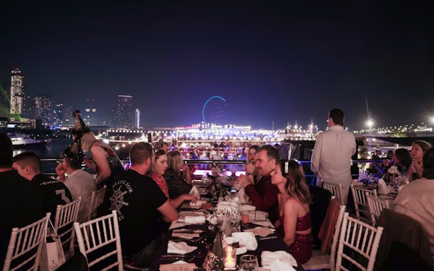 Guests dining on a New Year's Eve Marina Dhow Dinner Cruise with city skyline views.