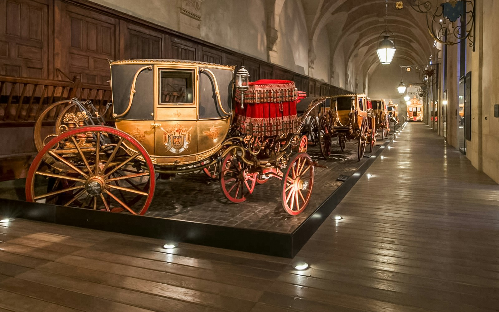 Ein opulenter Raum im Schloss Versailles mit goldenen Verzierungen und Gemälden an der Decke