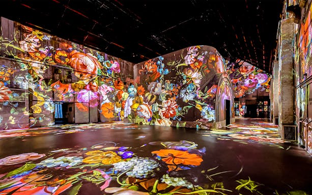 Floral projections on walls and floor at Fabrique des Lumières exhibition.