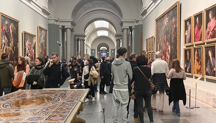 Group tour with guide at Prado Museum, Madrid, viewing art exhibition.