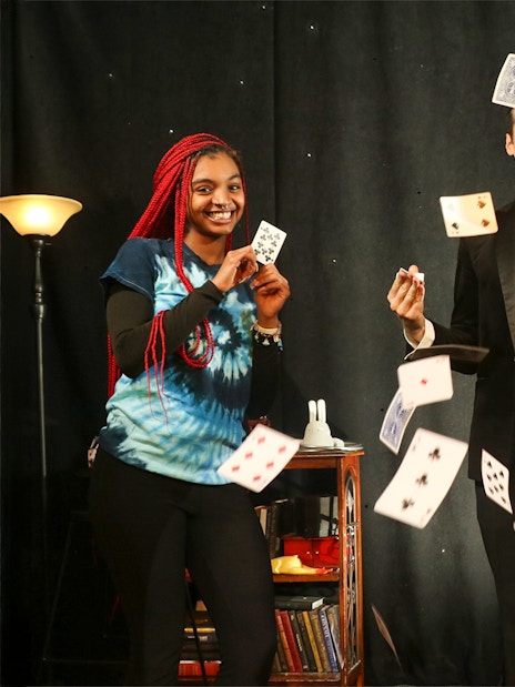 Magician performing card tricks with audience members on stage.