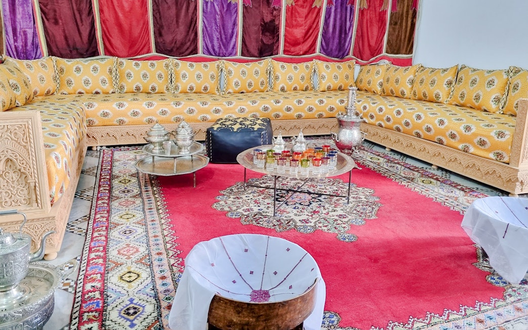 Traditional Moroccan salon with ornate seating and colorful decor in Bahia Palace, Marrakech.