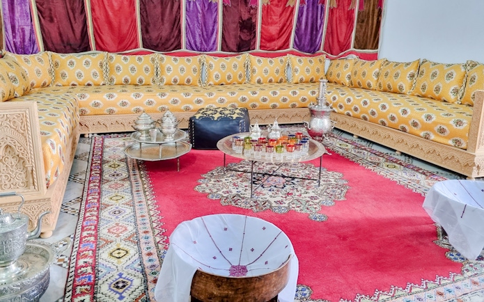 Traditional Moroccan salon with ornate seating and colorful decor in Bahia Palace, Marrakech.