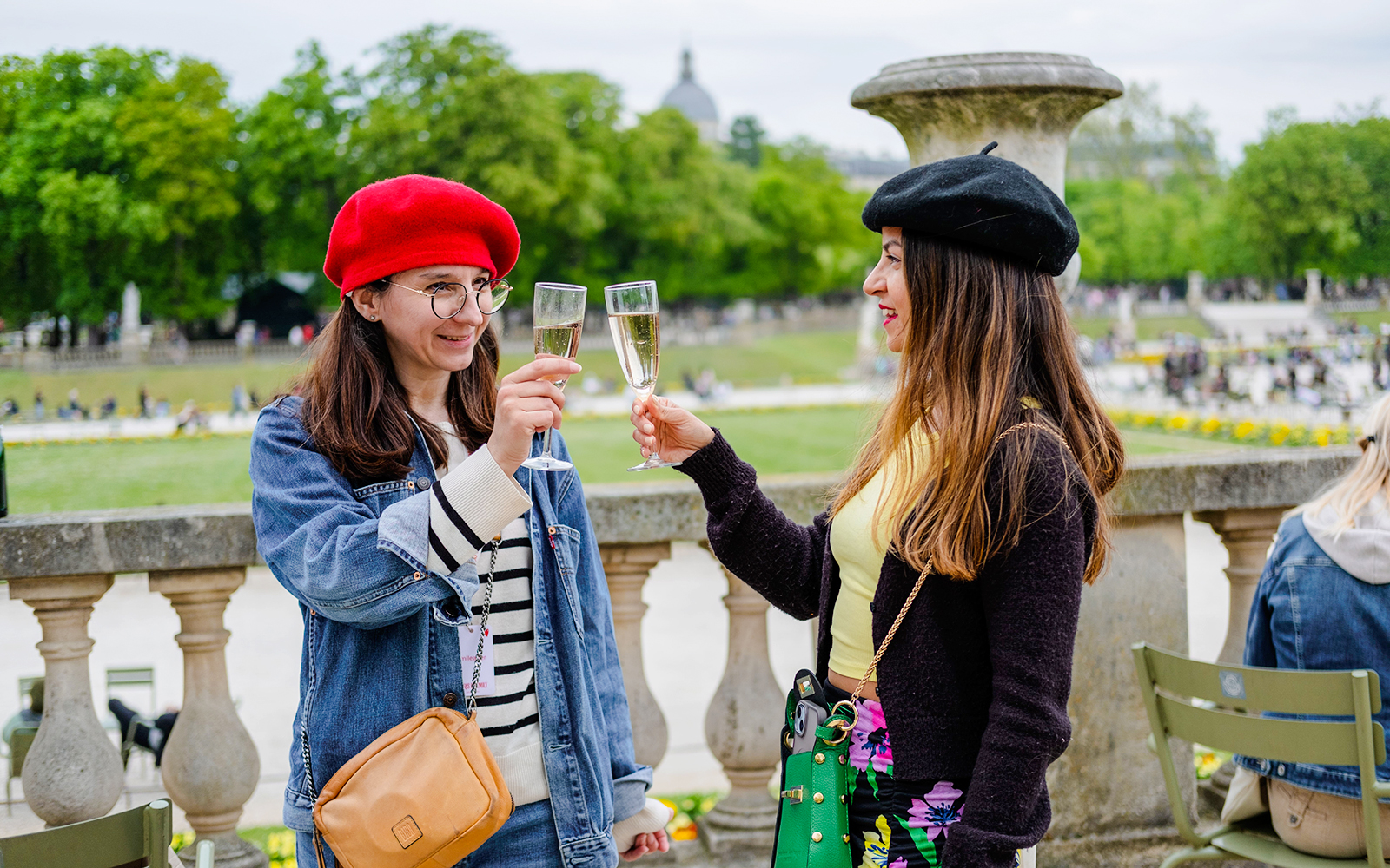 People clinking champagne glasses in a Paris park during Emily in Paris Food Tour.