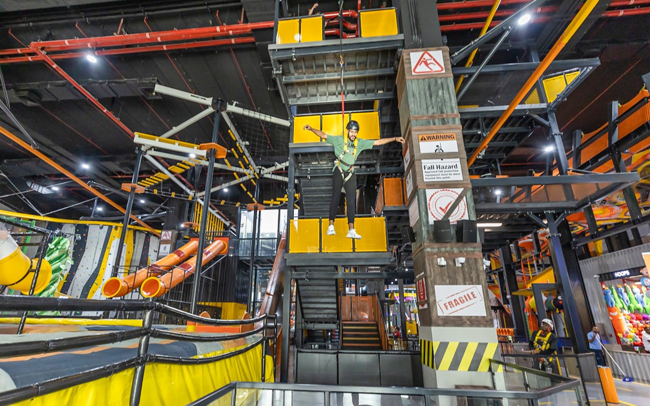 Person on a harness at Adrenark Adventure indoor obstacle course.