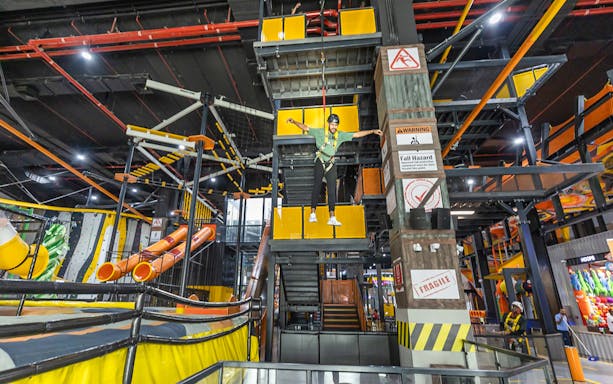 Person on a harness at Adrenark Adventure indoor obstacle course.