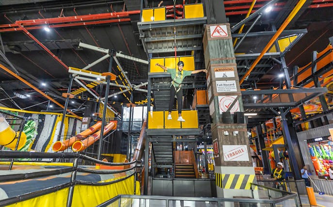 Person on a harness at Adrenark Adventure indoor obstacle course.