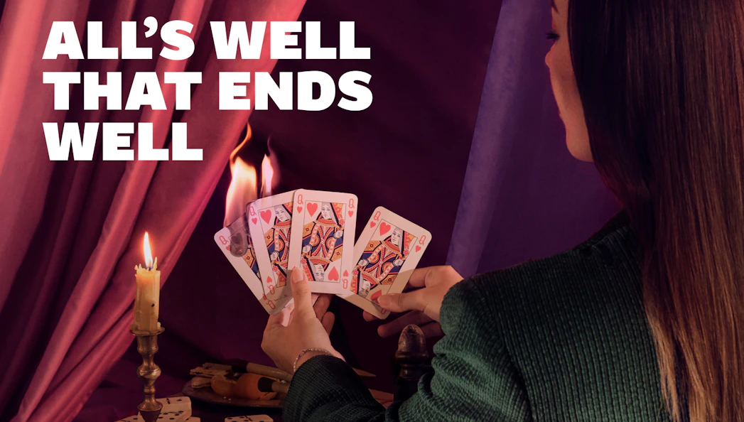 Person holding playing cards near candle with "All's Well that Ends Well" text.