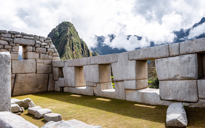 Temple of Three Windows at Machu Picchu with mountain backdrop.