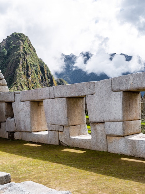 Temple of Three Windows at Machu Picchu with mountain backdrop.