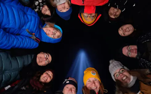Group of people smiling under the Imagine Peace Tower light during a guided tour in Reykjavik.