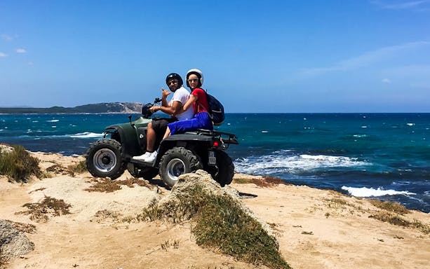 Two people on a quad bike by the sea in Santa Teresa di Gallura.