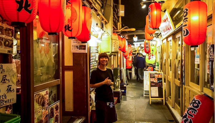 Asakusa street with red lanterns and a smiling guide during Tokyo family food tour.