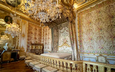 Queens apartment at Versailles Palace with ornate bed and chandelier.