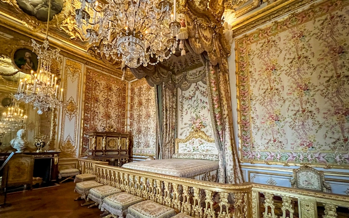 Queens apartment at Versailles Palace with ornate bed and chandelier.