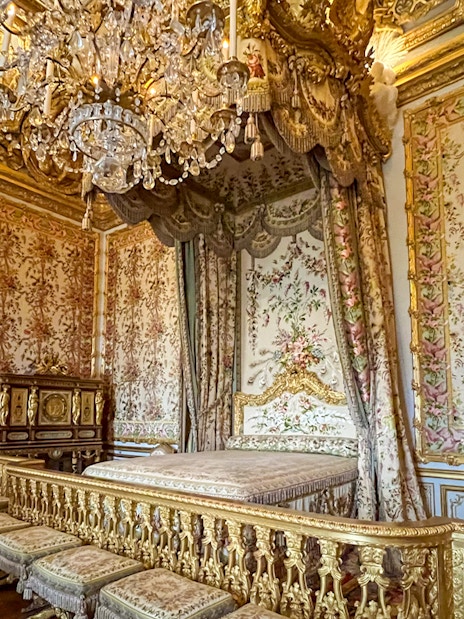 Queens apartment at Versailles Palace with ornate bed and chandelier.