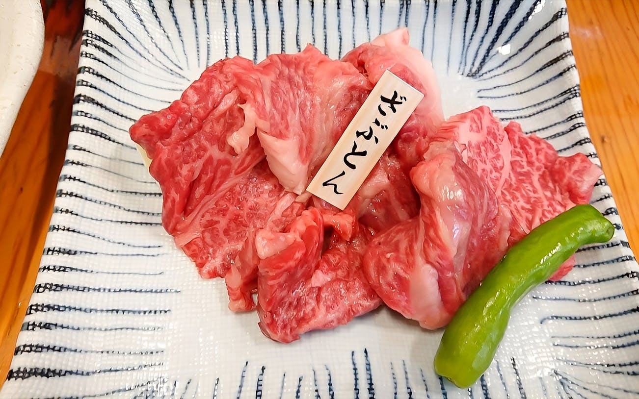 Wagyu beef slices with a green pepper on a patterned plate at Nikusen Tonya.