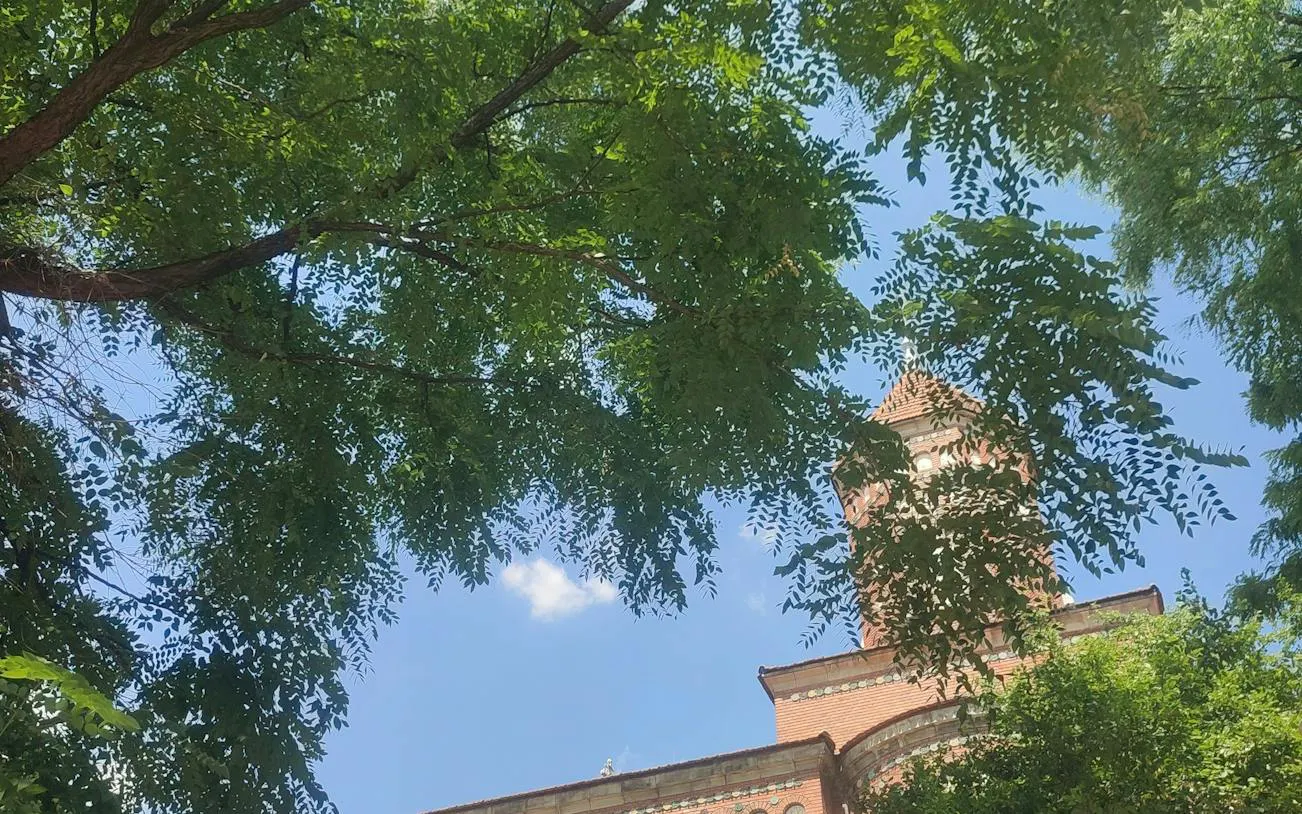 Carol Park tower partially visible through green trees, Bucharest.