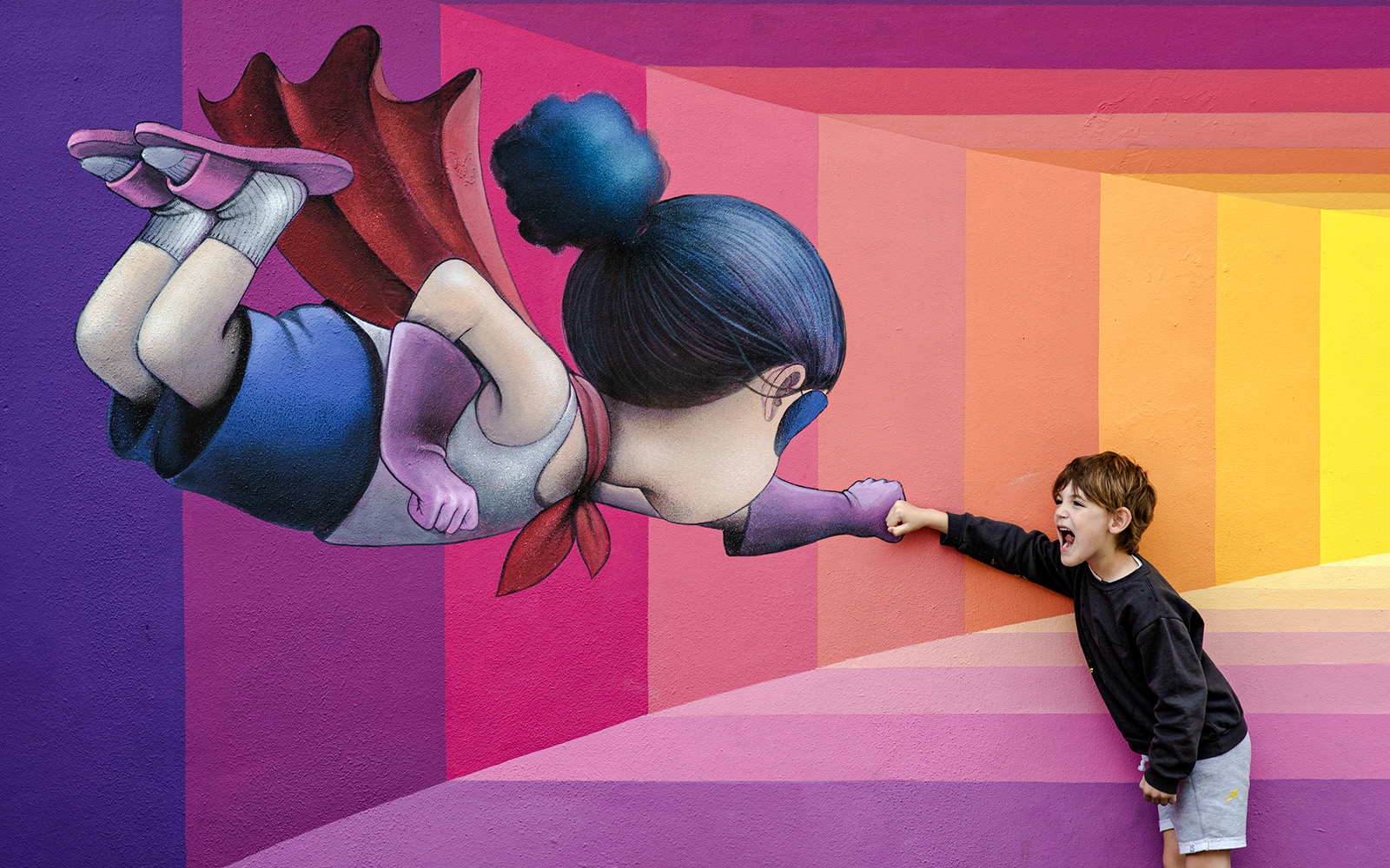 Child interacting with superhero mural at Wynwood Walls Museum.