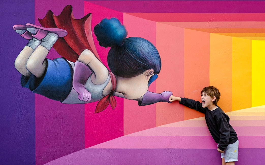 Child interacting with superhero mural at Wynwood Walls Museum.