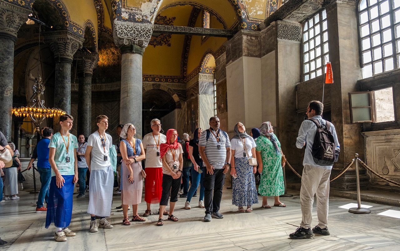 Guided tour group inside Hagia Sophia, Istanbul, observing architectural details.