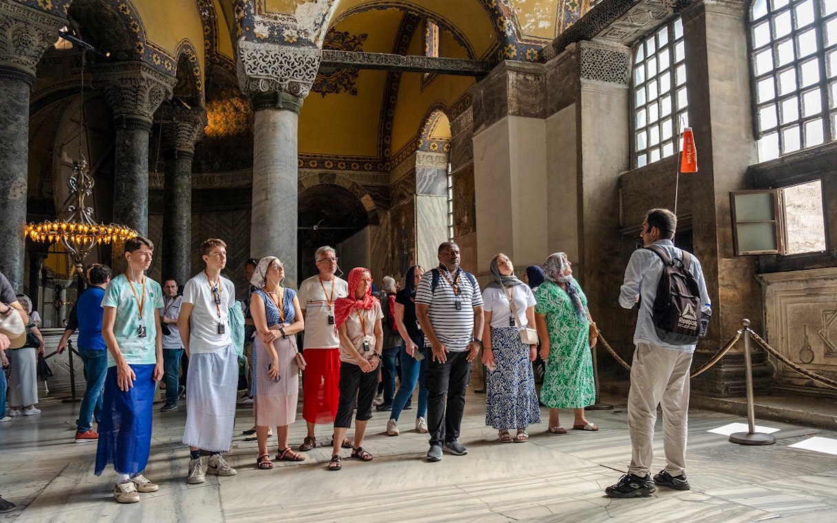 Guided tour group inside Hagia Sophia, Istanbul, observing architectural details.