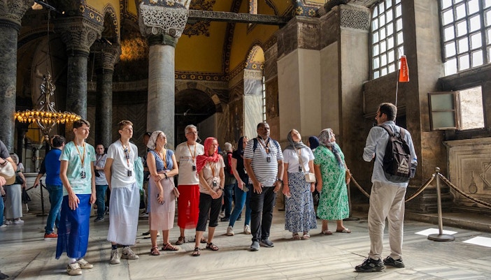 Guided tour group inside Hagia Sophia, Istanbul, observing architectural details.