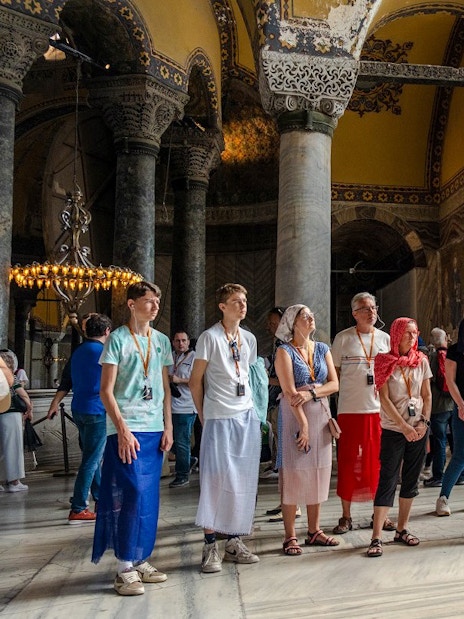 Guided tour group inside Hagia Sophia, Istanbul, observing architectural details.